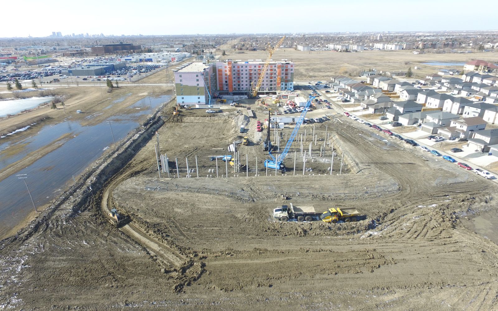 Aerial view of a site development with a piling rig and cranes on site