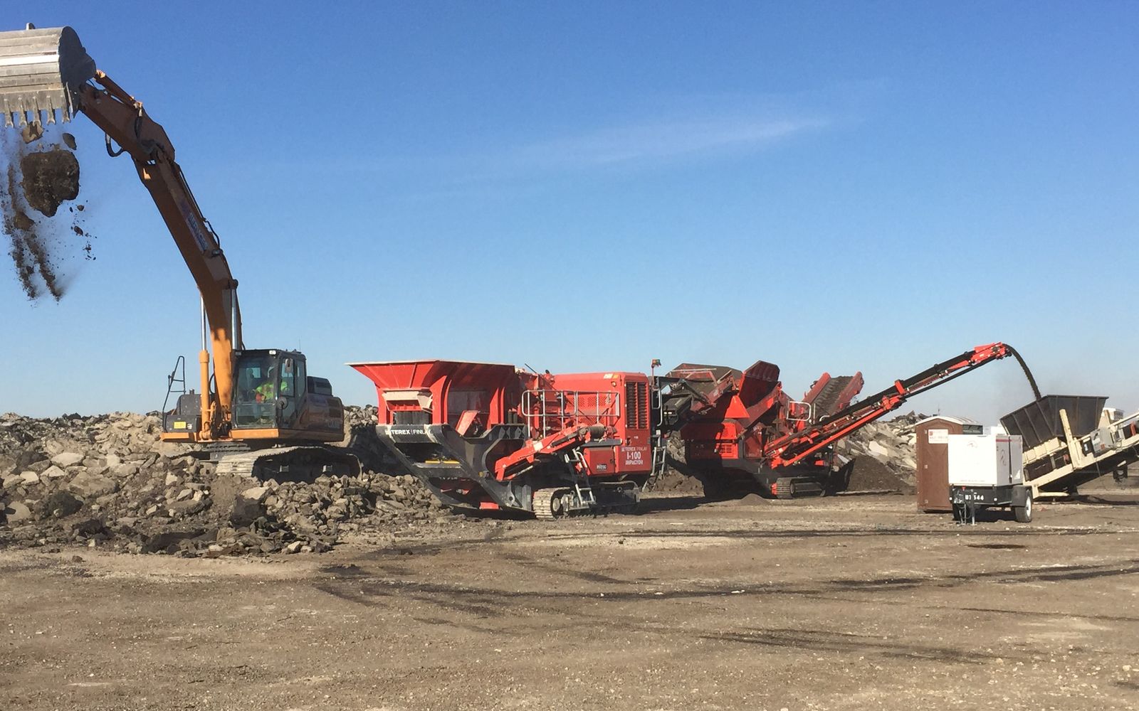 Excavator tipping concrete into the crusher hopper