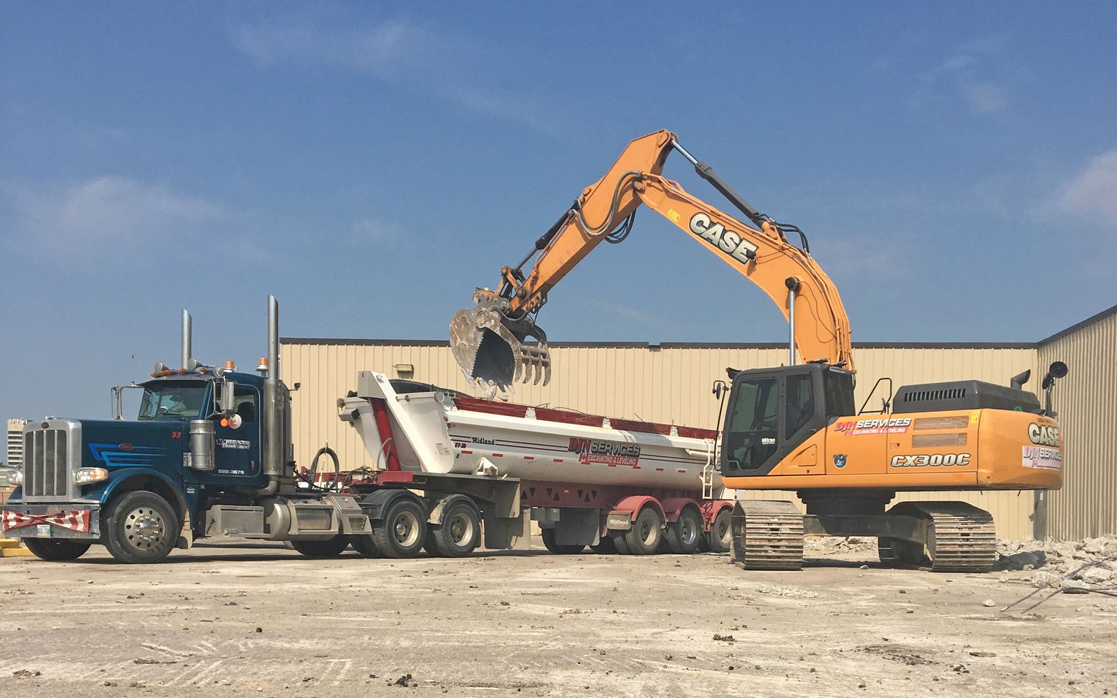 DJN excavator with a grapple attachment loading an end dump