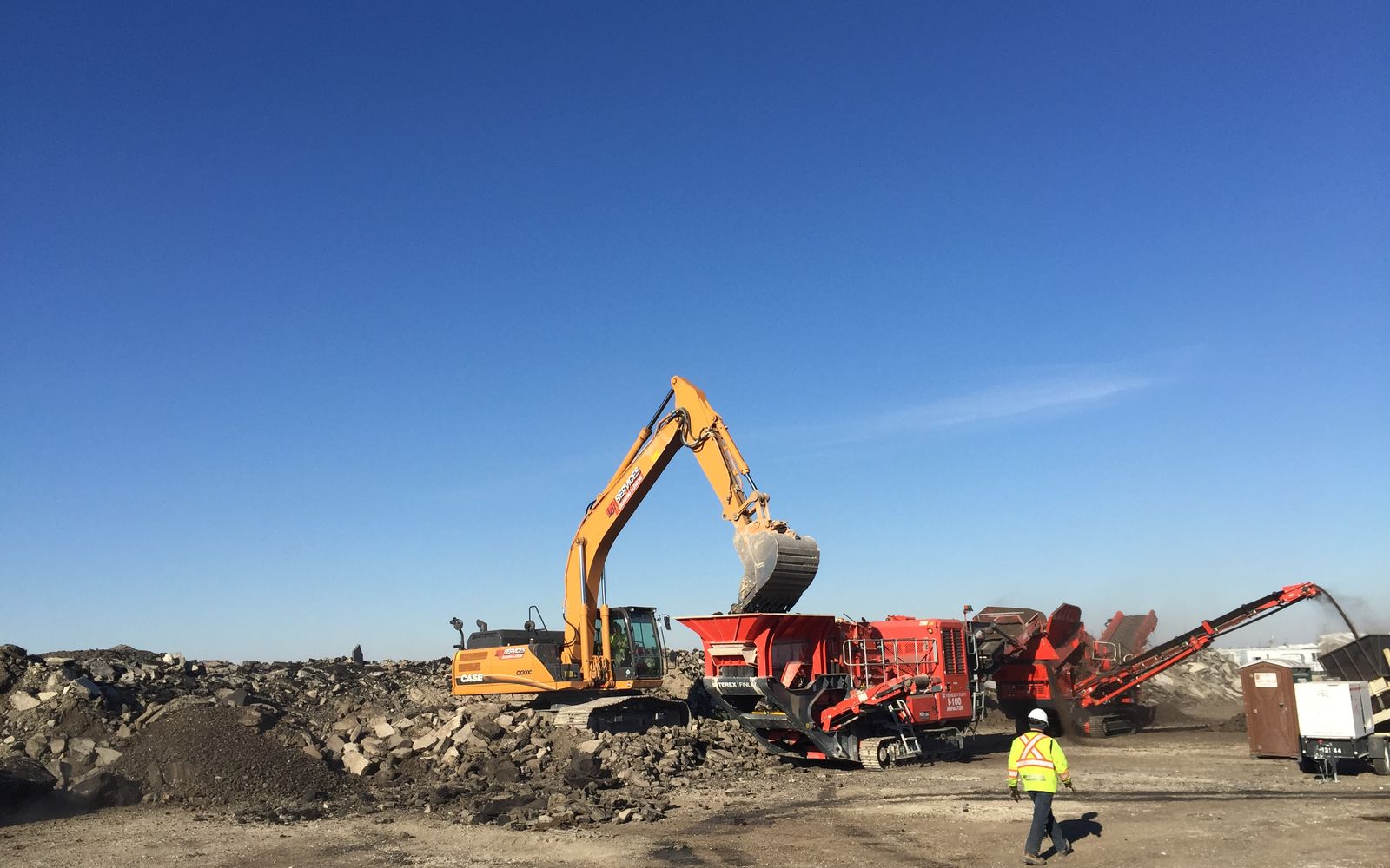 DJN excavator feeding the mobile crusher under blue sky